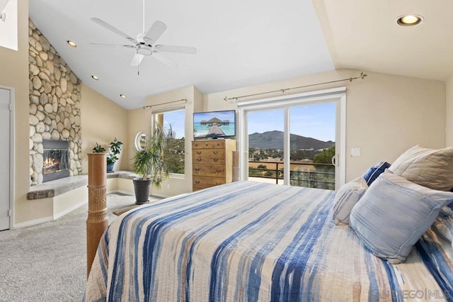 carpeted bedroom featuring vaulted ceiling, ceiling fan, access to outside, and a stone fireplace