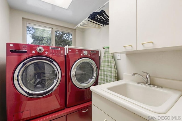 clothes washing area with sink, separate washer and dryer, and cabinets