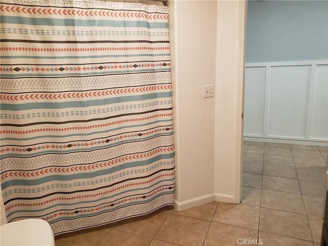 11710 Paskenta Rd, Red Bluff, CA 96080 - bathroom with a decorative wall, wainscoting, toilet, tile patterned flooring, and a shower with shower curtain