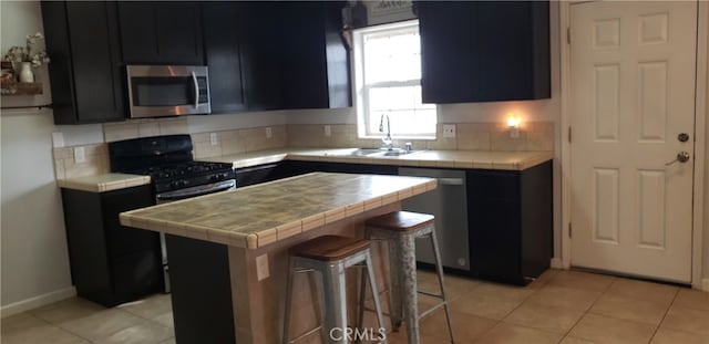 kitchen with sink, stainless steel appliances, backsplash, and tile counters