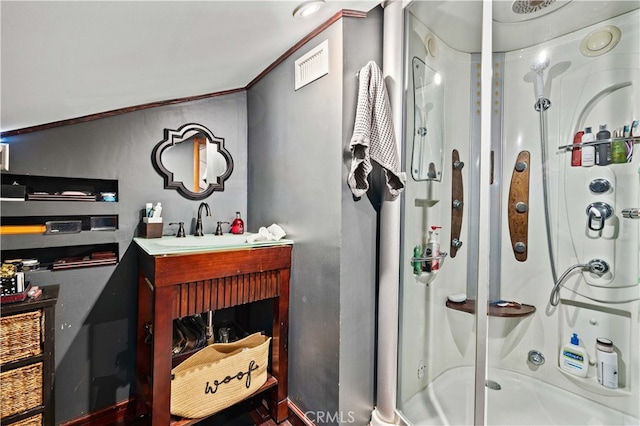 bathroom featuring crown molding, vanity, and a shower with shower door