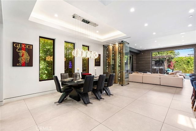 dining area with a wealth of natural light, a raised ceiling, and light tile patterned floors