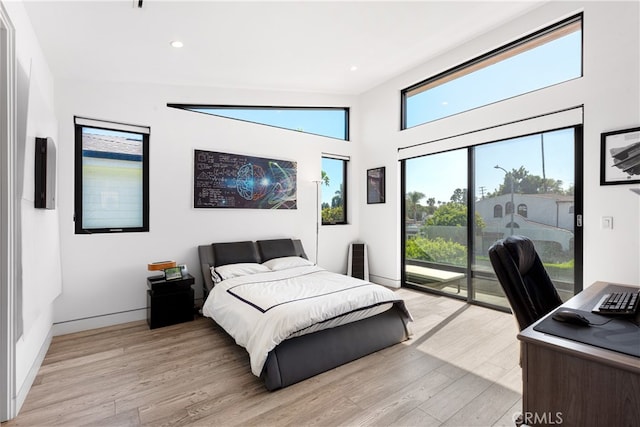 bedroom featuring light wood-type flooring, vaulted ceiling, and access to exterior