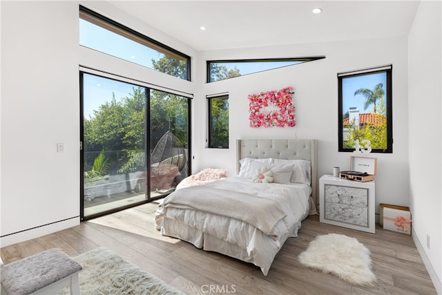 bedroom featuring light hardwood / wood-style floors, lofted ceiling, and access to exterior