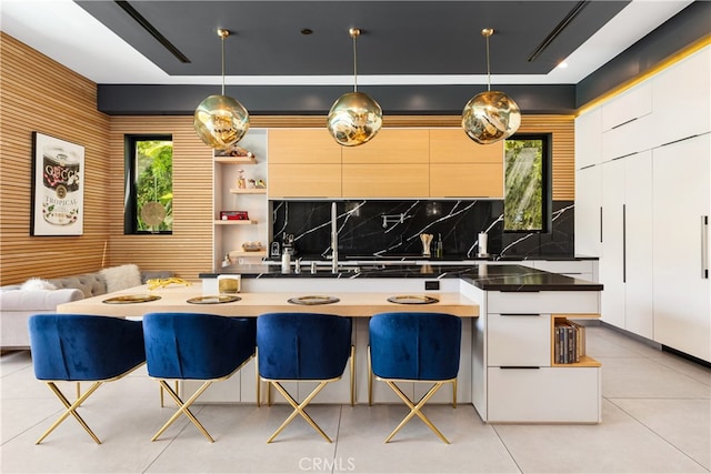 kitchen with hanging light fixtures, tasteful backsplash, white cabinetry, and a breakfast bar