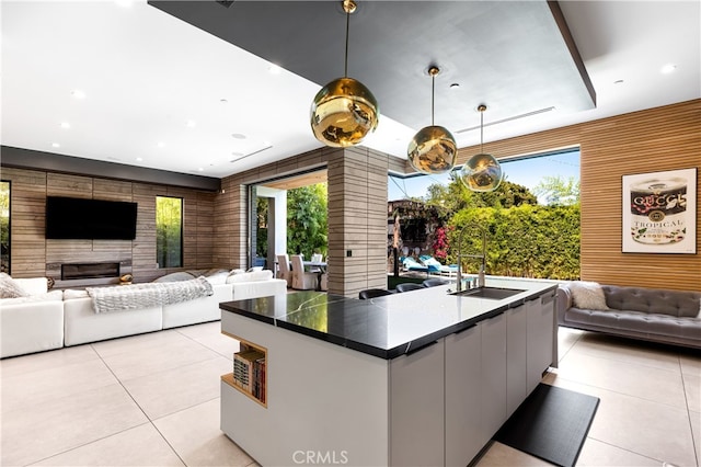 kitchen featuring pendant lighting, a large island with sink, light tile patterned flooring, and sink