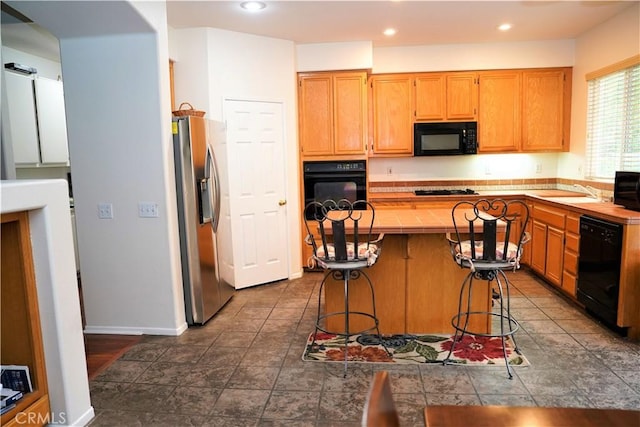 kitchen featuring black appliances, sink, a kitchen breakfast bar, and a center island