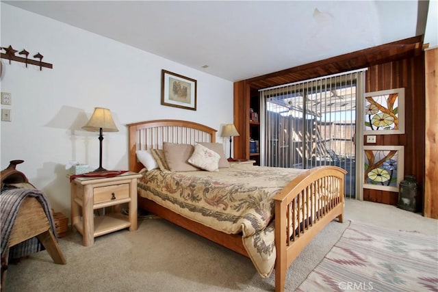 carpeted bedroom with wood walls and access to outside