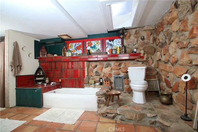 bathroom with a bathing tub, toilet, backsplash, and tile patterned floors