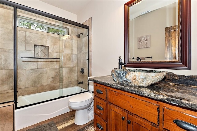 full bathroom featuring vanity, hardwood / wood-style floors, toilet, and combined bath / shower with glass door