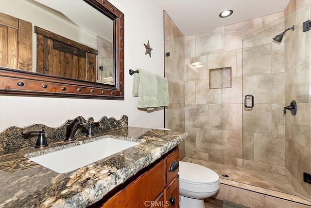 bathroom featuring a shower with door, vanity, and toilet