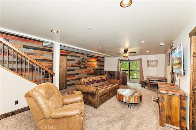 carpeted living room with ceiling fan and wood walls