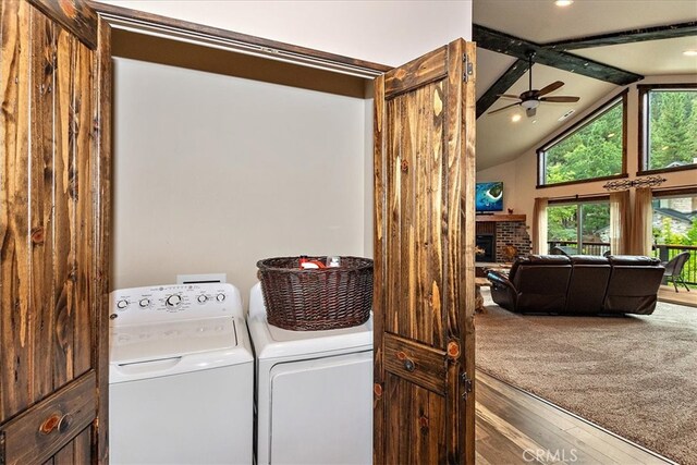 clothes washing area with separate washer and dryer, a fireplace, ceiling fan, and hardwood / wood-style flooring