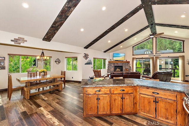 kitchen featuring dark stone countertops, beam ceiling, a fireplace, and dark hardwood / wood-style flooring