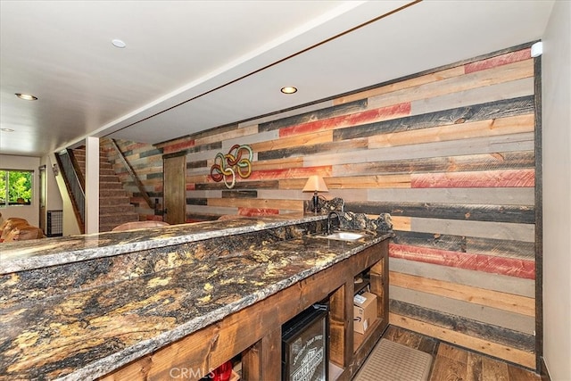 bar featuring dark stone counters, sink, and dark hardwood / wood-style flooring