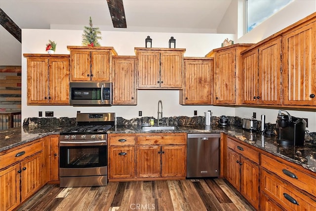 kitchen featuring sink, appliances with stainless steel finishes, dark hardwood / wood-style floors, dark stone counters, and vaulted ceiling