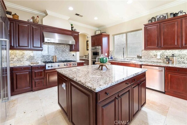 kitchen featuring a kitchen island, decorative backsplash, stainless steel appliances, extractor fan, and crown molding