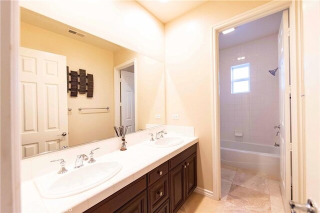 bathroom featuring tiled shower / bath combo and vanity