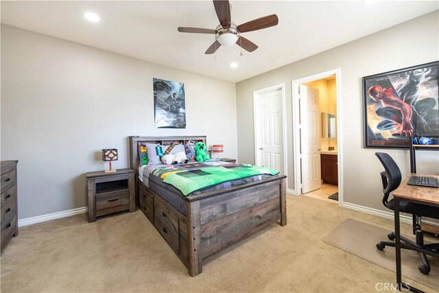 bedroom featuring ceiling fan, light colored carpet, and ensuite bathroom