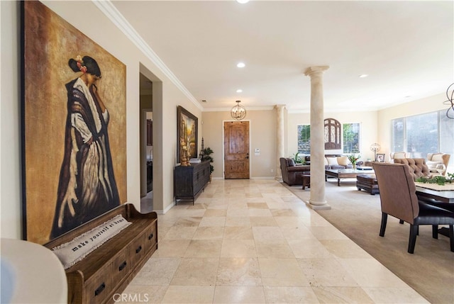 hall featuring ornate columns, light carpet, an inviting chandelier, and ornamental molding