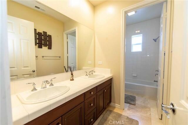 bathroom with tiled shower / bath combo and vanity