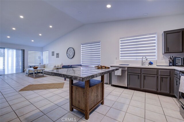 kitchen with lofted ceiling, light tile patterned floors, sink, stainless steel appliances, and a kitchen bar