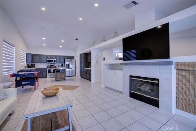 tiled living room with a tiled fireplace and high vaulted ceiling