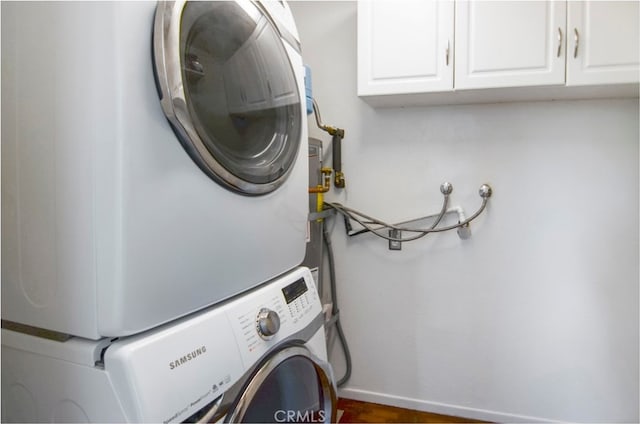 clothes washing area with cabinets and stacked washer and dryer