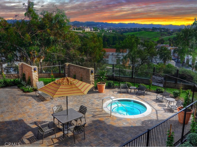 pool at dusk with a community hot tub and a patio