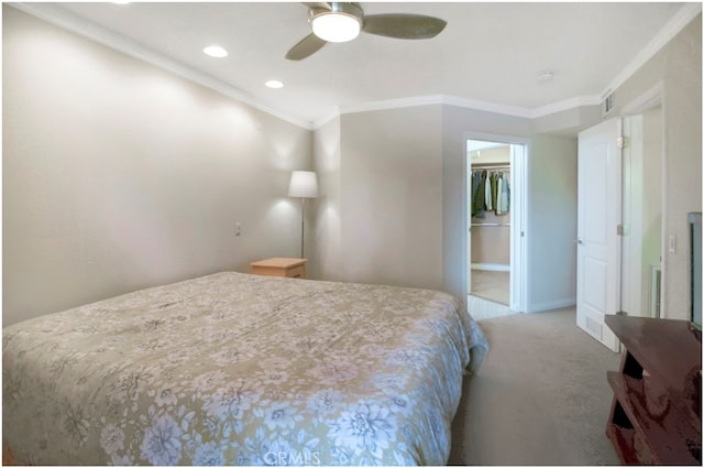 carpeted bedroom with ornamental molding, a closet, ceiling fan, and a walk in closet