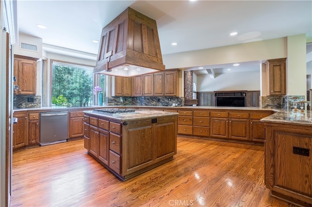 kitchen with backsplash, light hardwood / wood-style floors, a center island, and stainless steel appliances