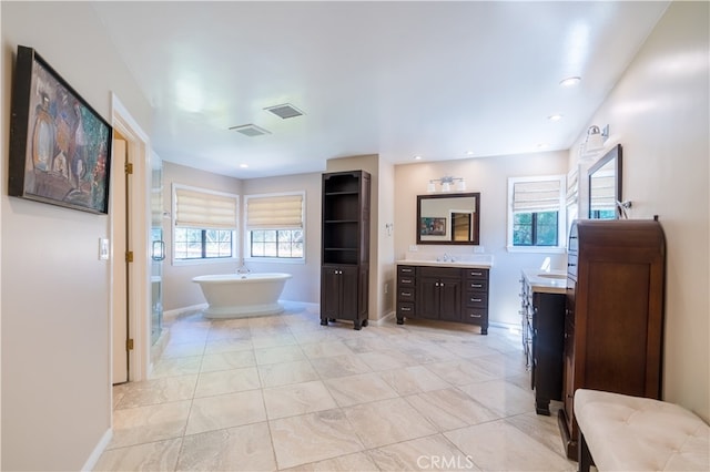 bathroom with a healthy amount of sunlight, vanity, and a tub