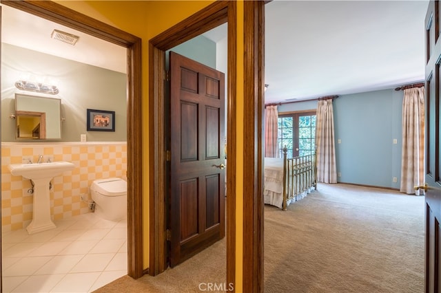 hallway with light colored carpet and tile walls