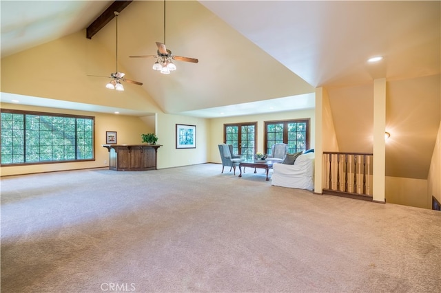 unfurnished living room featuring high vaulted ceiling, beam ceiling, ceiling fan, and carpet