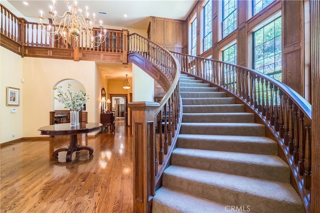 stairway featuring an inviting chandelier, a high ceiling, and hardwood / wood-style floors