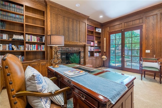 carpeted office space featuring wood walls, a brick fireplace, ornamental molding, french doors, and built in features