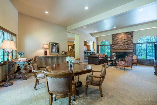 dining area featuring a healthy amount of sunlight, a fireplace, and light carpet