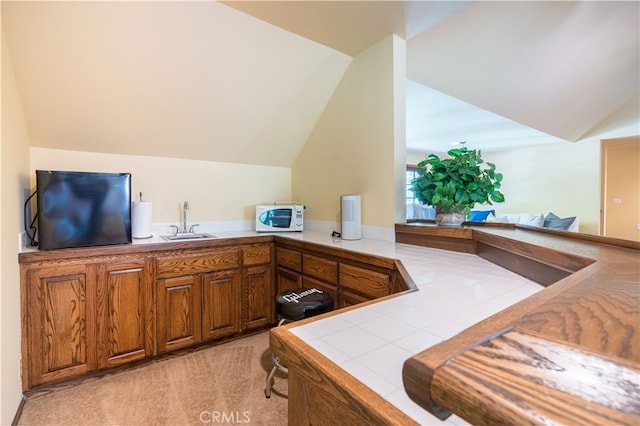 interior space featuring black fridge, sink, tile counters, light carpet, and vaulted ceiling