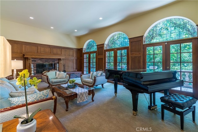 sitting room featuring a brick fireplace, a high ceiling, light colored carpet, and french doors