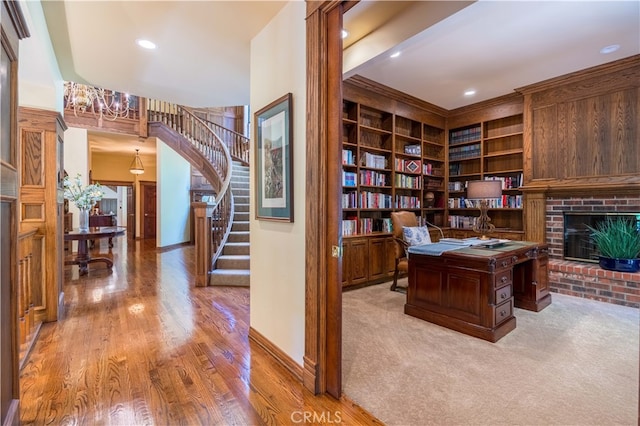 home office featuring a brick fireplace, light hardwood / wood-style floors, and built in shelves