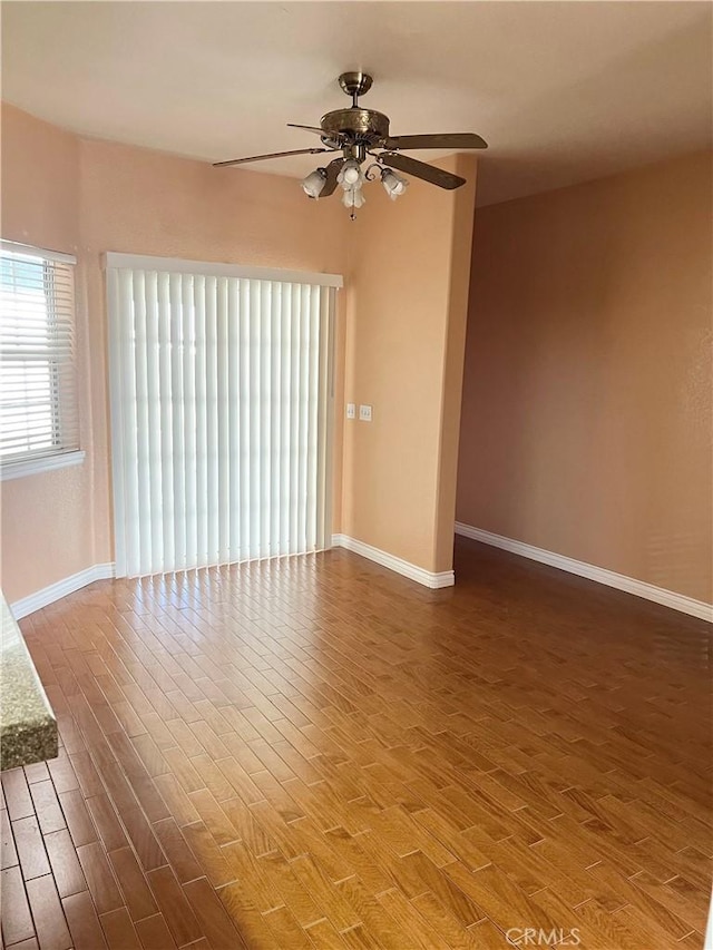 empty room with ceiling fan, baseboards, and wood finished floors