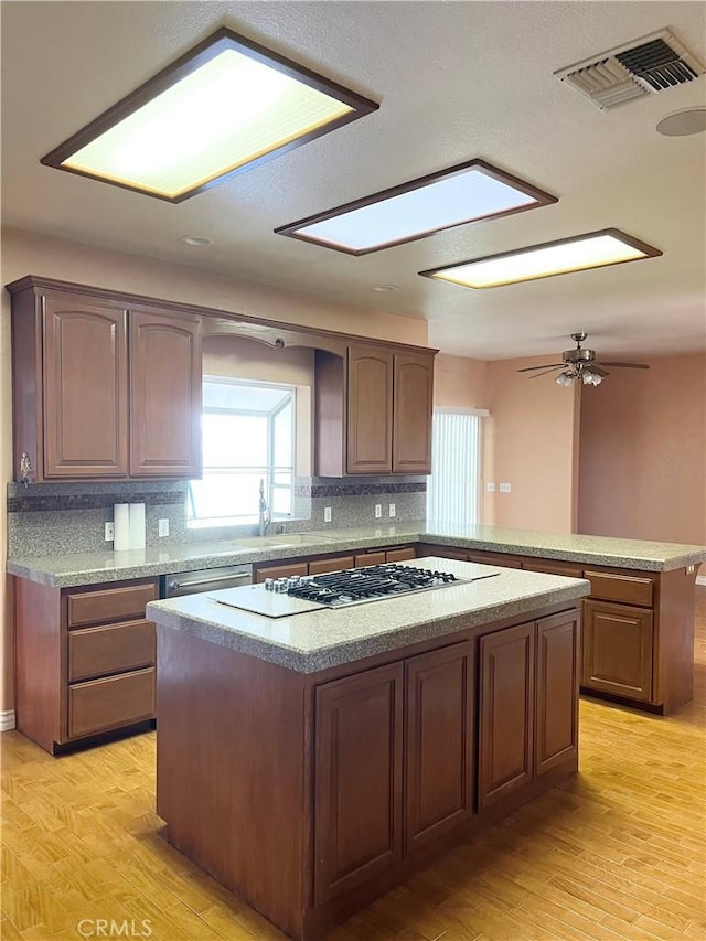 kitchen featuring visible vents, light wood-style flooring, appliances with stainless steel finishes, a center island, and a peninsula