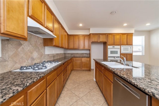 kitchen with white appliances, dark stone counters, sink, decorative backsplash, and light tile patterned flooring