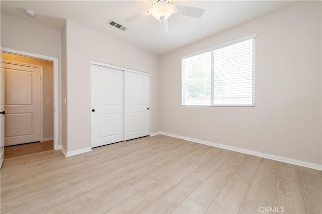 unfurnished bedroom featuring ceiling fan, a closet, and light wood-type flooring