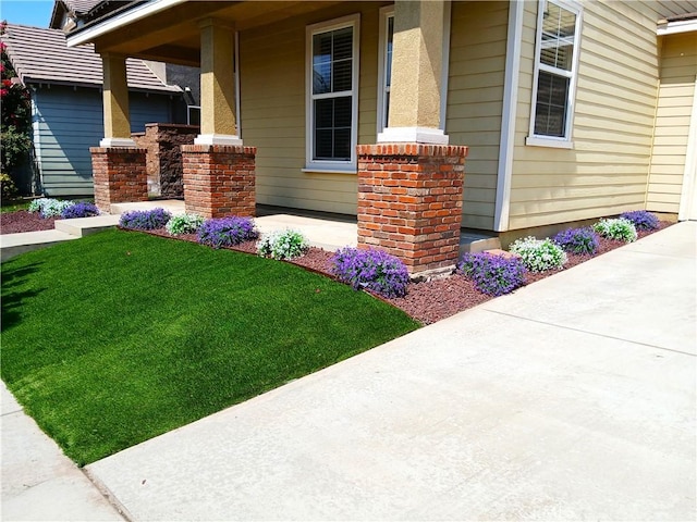 view of side of home featuring a lawn and covered porch