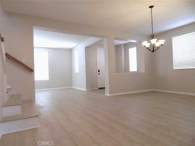 unfurnished living room with light hardwood / wood-style floors and a notable chandelier