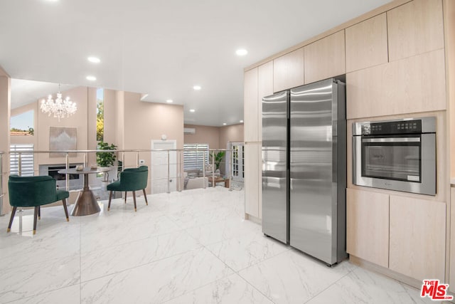 kitchen with appliances with stainless steel finishes, a notable chandelier, light brown cabinets, and decorative light fixtures