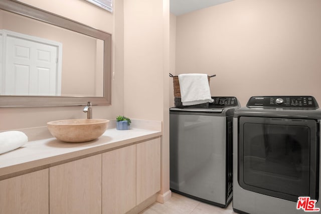 laundry area with washer and clothes dryer, light tile patterned flooring, and sink