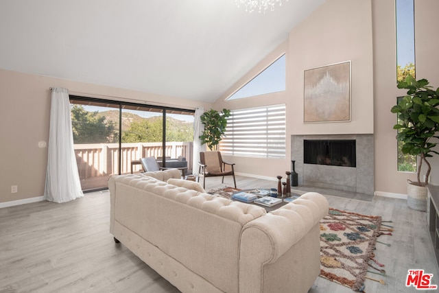 living room featuring high vaulted ceiling, a high end fireplace, and light hardwood / wood-style flooring