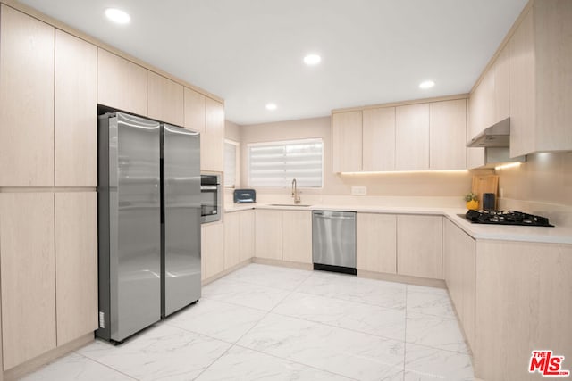 kitchen featuring light brown cabinetry, appliances with stainless steel finishes, sink, and extractor fan